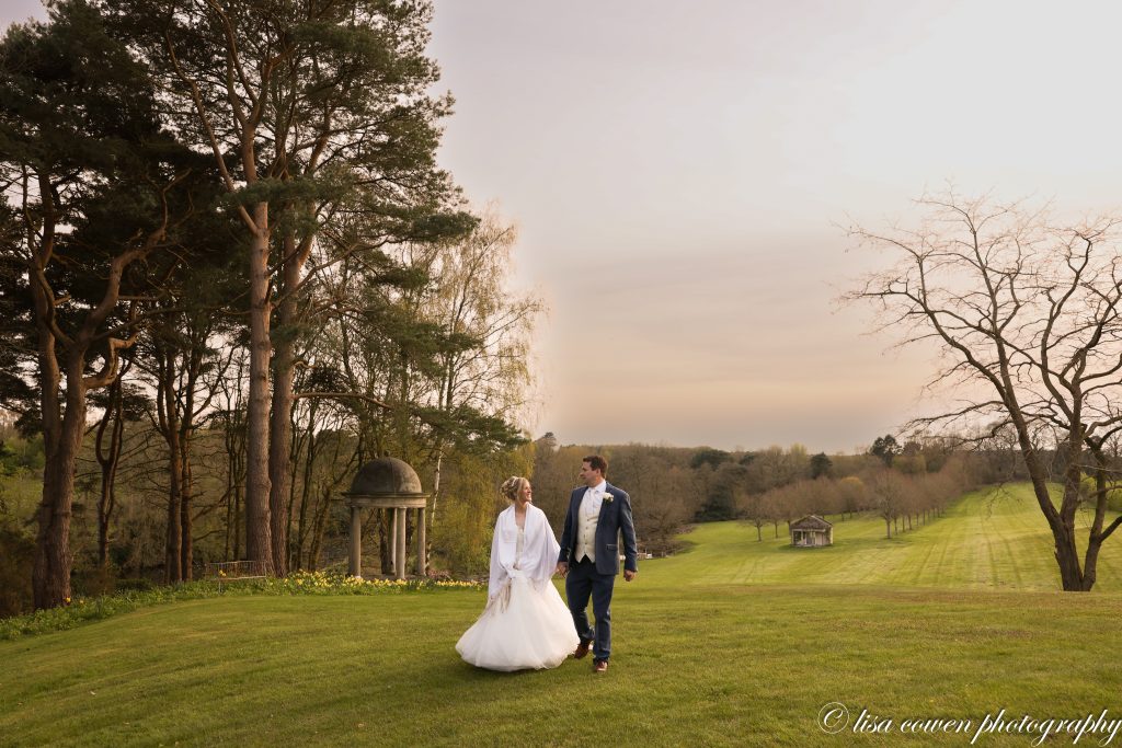 Bride and groom walking hand in hand through the incredible, manicured grounds of Delamere Manor.
