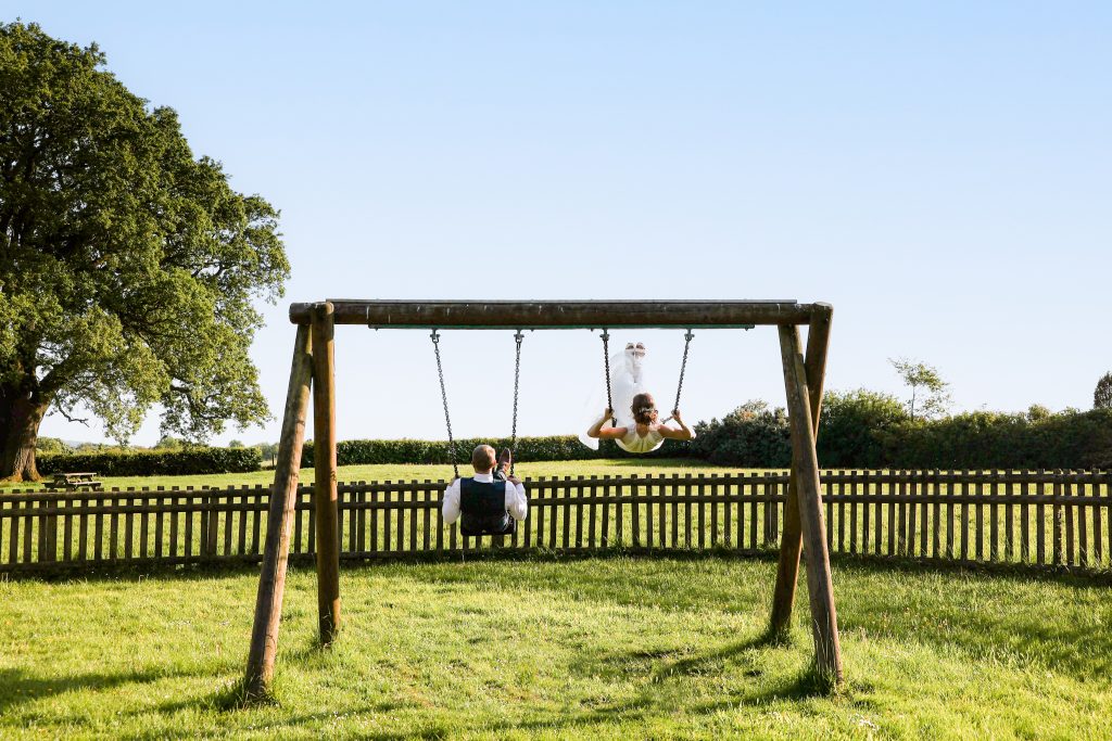 Bride and groom playing on the swings at the local park.