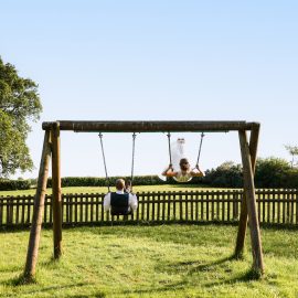 Bride and groom playing on the swings at the local park.
