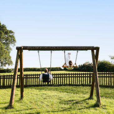 Bride and groom playing on the swings at the local park.