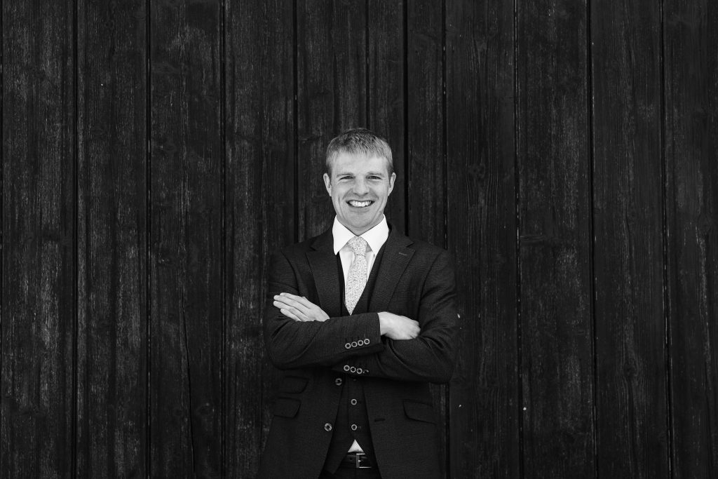 Groom with arms folded in black and white