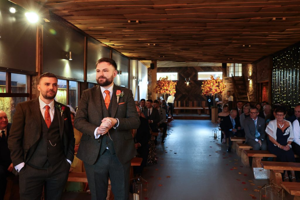 The groom looking nervous and excited while waiting at the altar in the ceremony barn at Owen House Wedding Barn