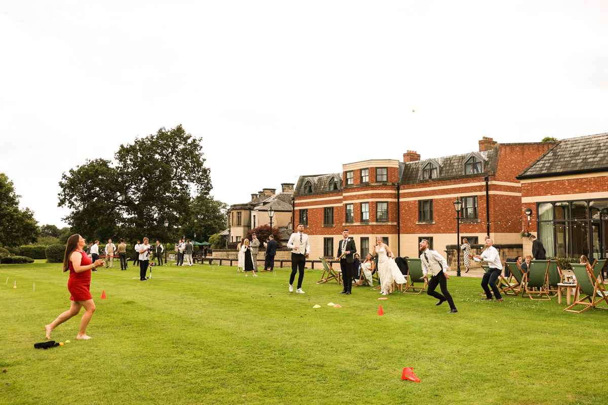 Wedding guests playing lawn games on the grass outside Rookery Hall during a wedding reception.