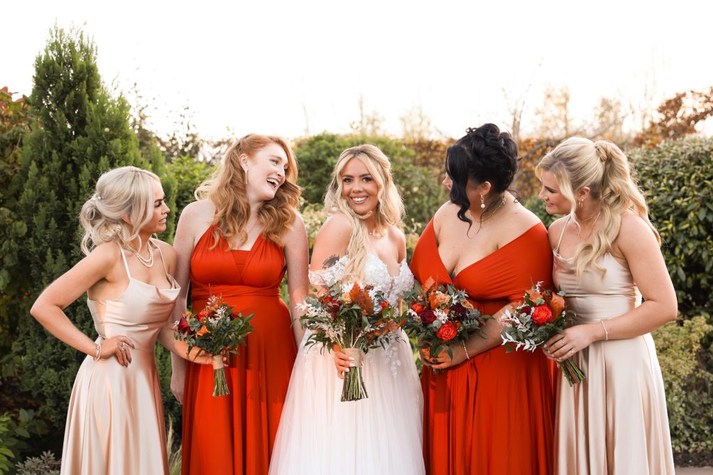 The bride and bridesmaids laughing together in the courtyard at Owen House Wedding Barn