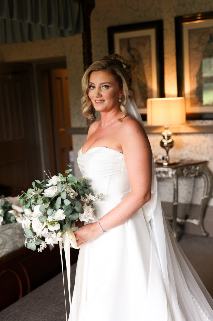 a beautiful bridal portrait with the bride holding a bouquet in a white gown during preparations at Mitton Hall.