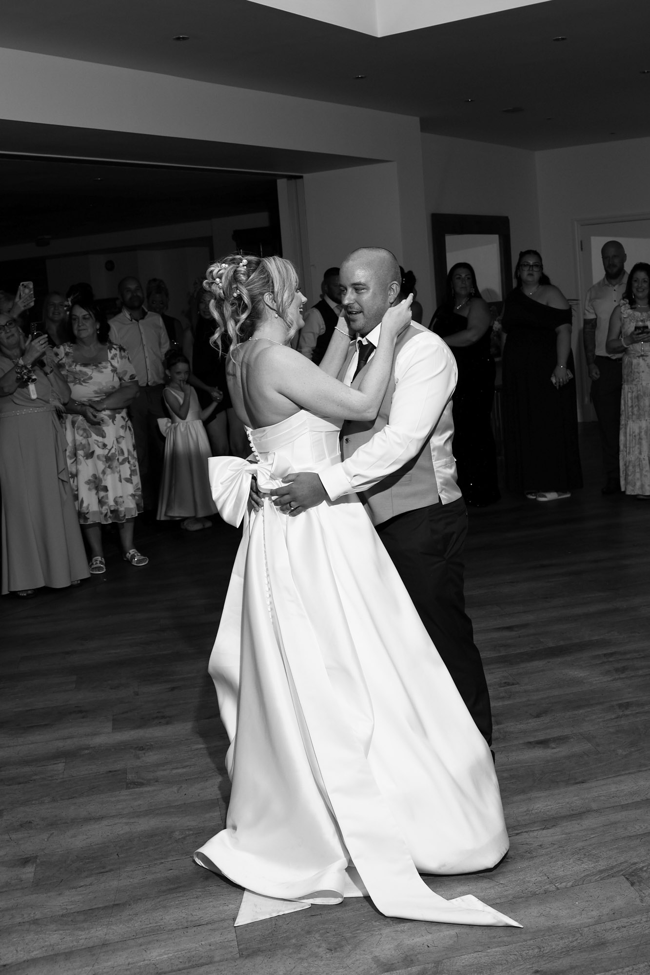 Black and white photo of the bride and groom sharing their first dance together as guests watch on at Mitton Hall.