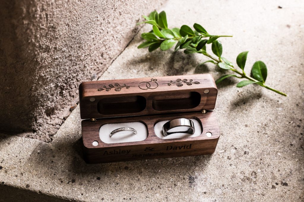 Wedding rings for the bride and groom resting inside an engraved wooden box at Mitton Hall.