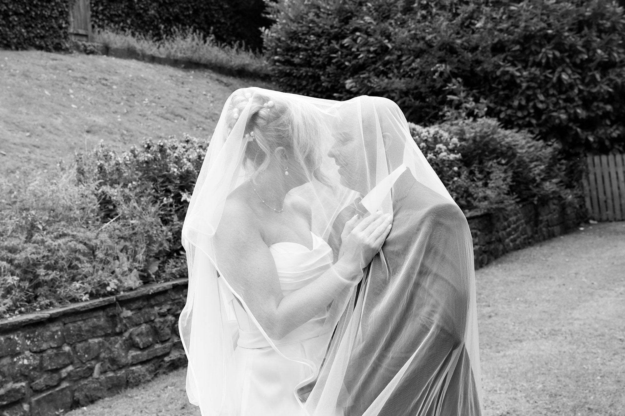 Black and white photo of the bride and groom sharing a tender moment together beneath the veil at Mitton Hall.