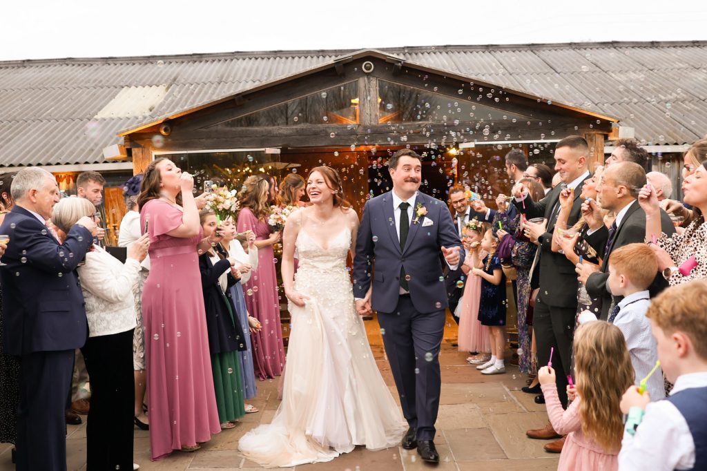 Newlyweds walking through a shower of magical bubbles after their ceremony at Owen House Wedding Barn
