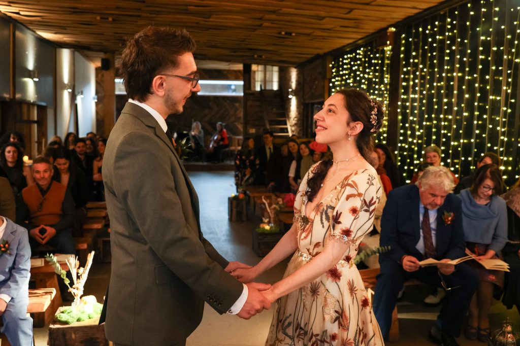 A tender, romantic moment as the bride and groom exchange vows in the ceremony barn at Owen House Wedding Barn
