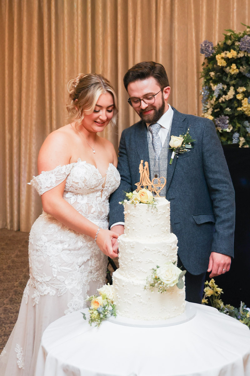 Bride and groom cutting a multi-tiered white wedding cake at Rookery Hall.