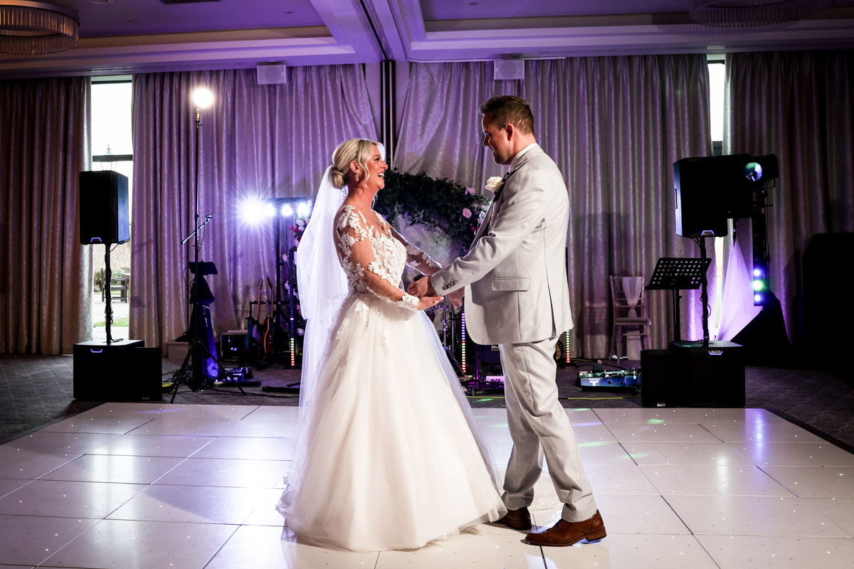 Newlywed couple sharing their first dance on an illuminated dance floor at Rookery Hall.