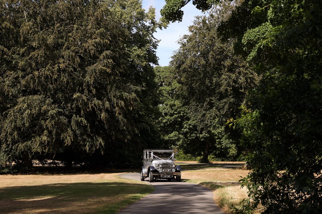 classic wedding car driving in the grounds of Meols Hall on the way to the tithe Barn