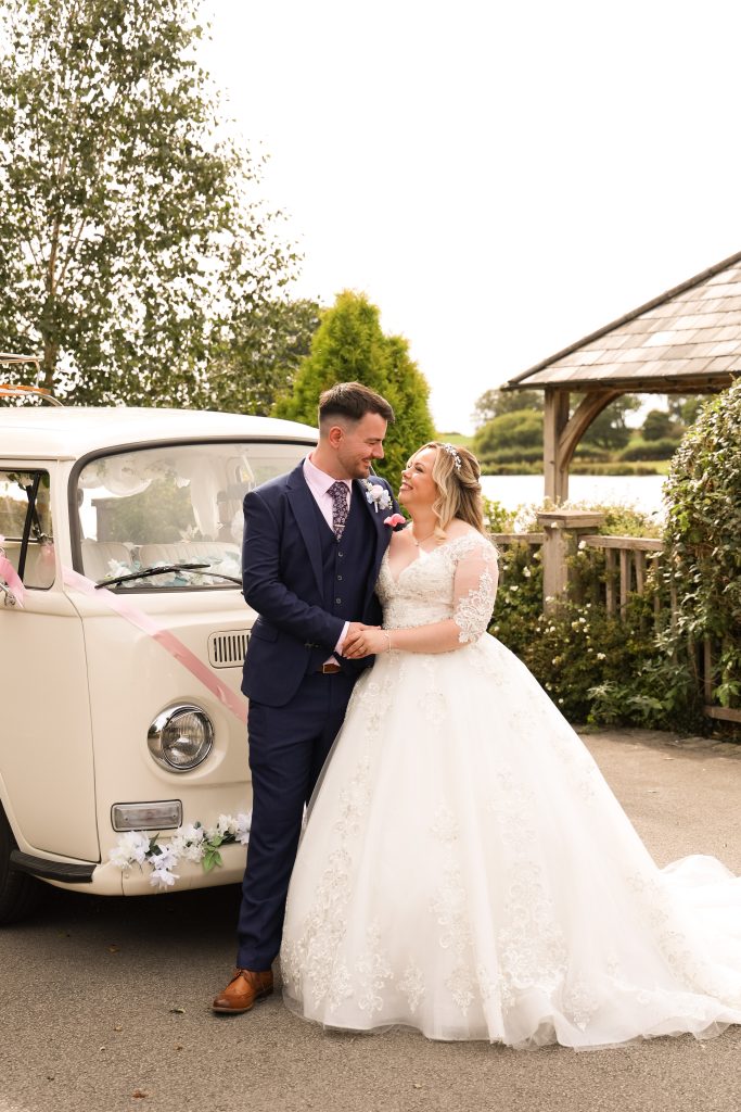 Bride and groom holding hands next to a cream vintage campervan.