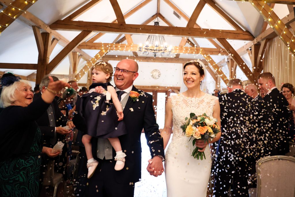 Happy newlyweds walking back up the aisle amidst a shower of confetti.
