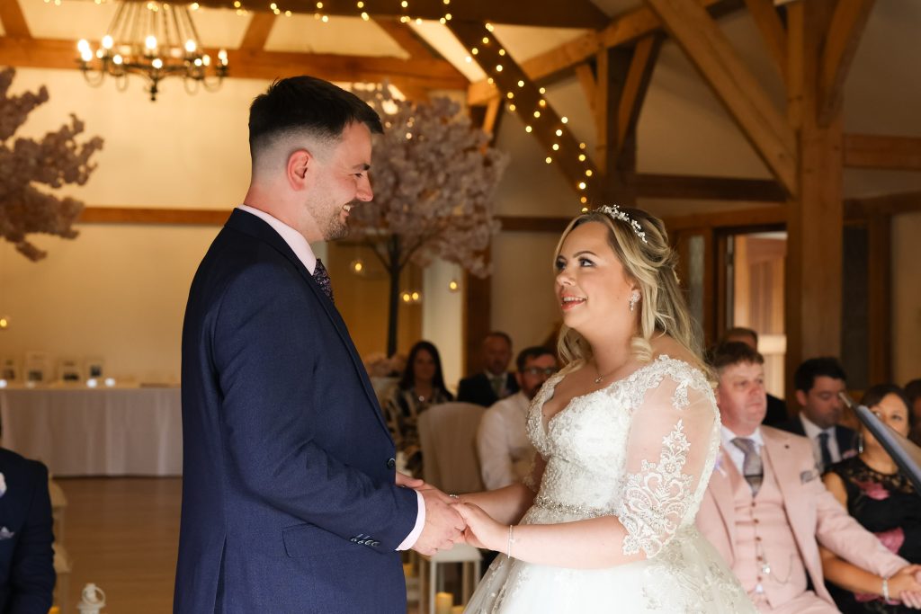 Bride and groom smiling at each other during their emotional indoor wedding ceremony.