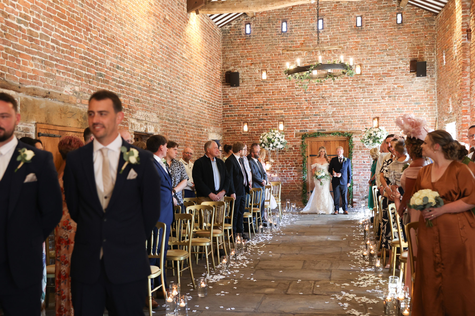 Bride and her father standing at the entrance of a rustic brick barn before walking down the aisle.