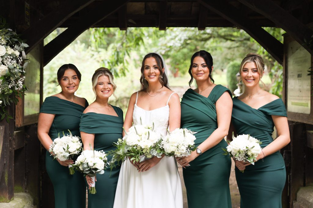 Close-up portrait of bride and four bridesmaids holding white flower bouquets.