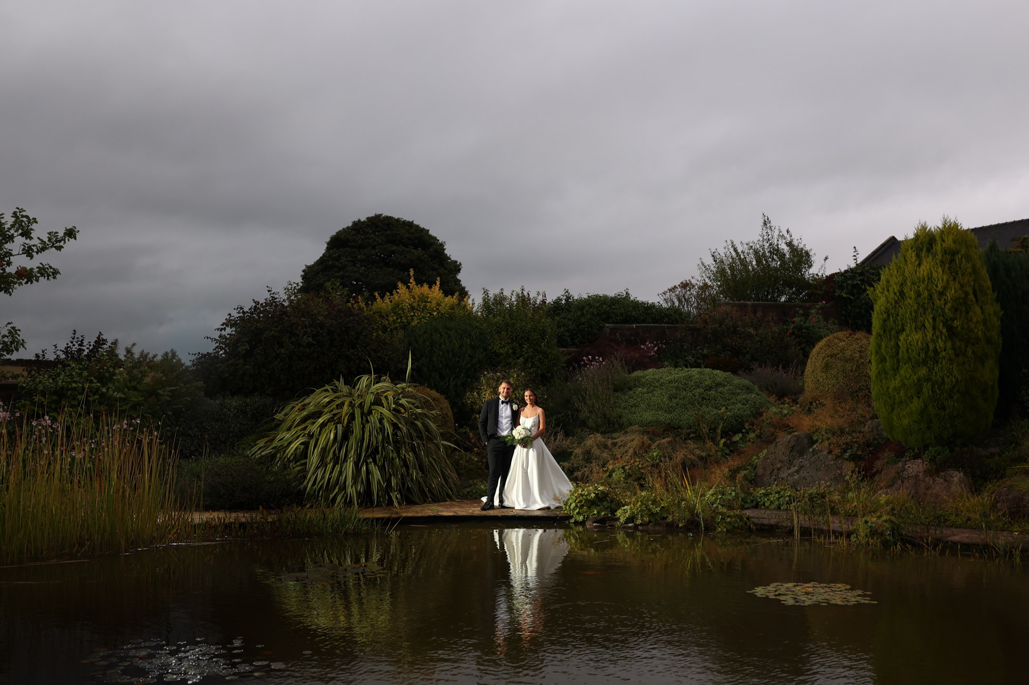 A beautiful bride and groom, lit by off-camera flash in the water garden at Heaton House Farm