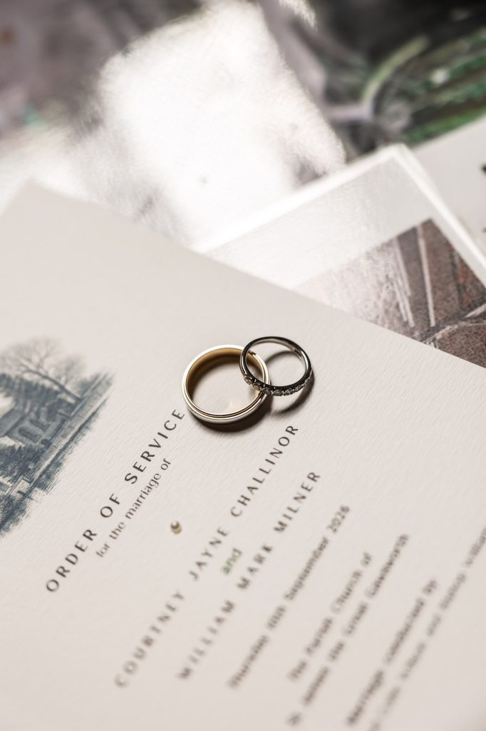 Close-up of two wedding bands resting on a printed Order of Service card.